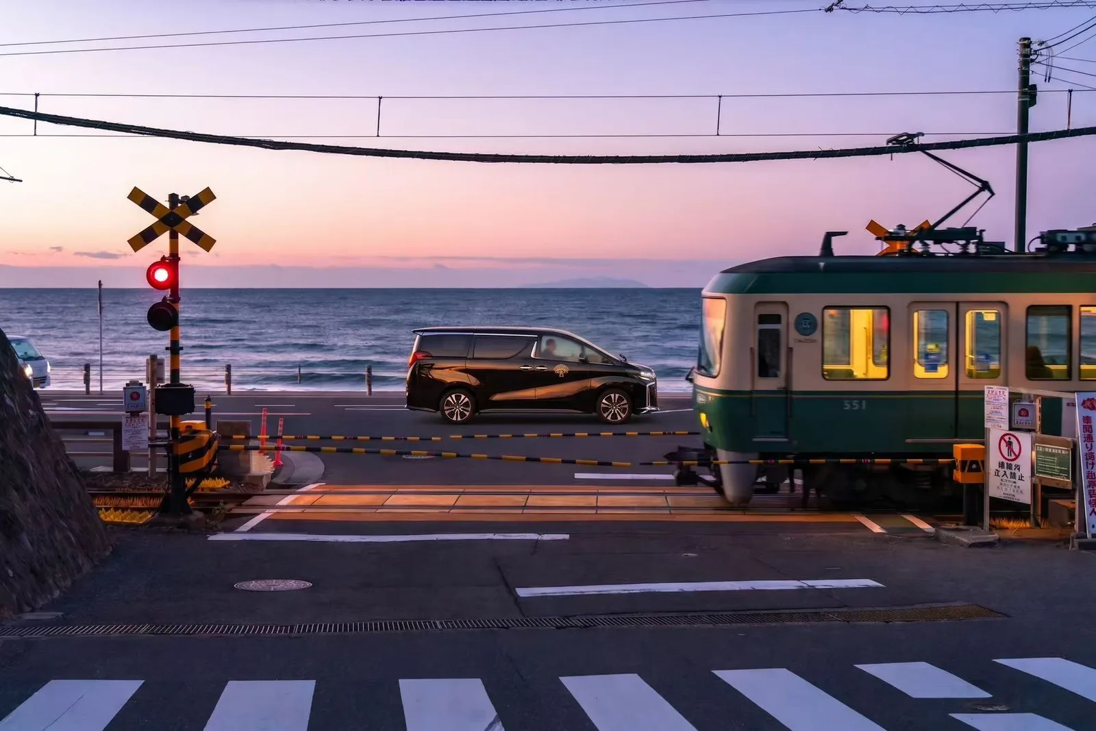 Black private chauffeur vehicle beside the Enoden railway on the Shonan coast